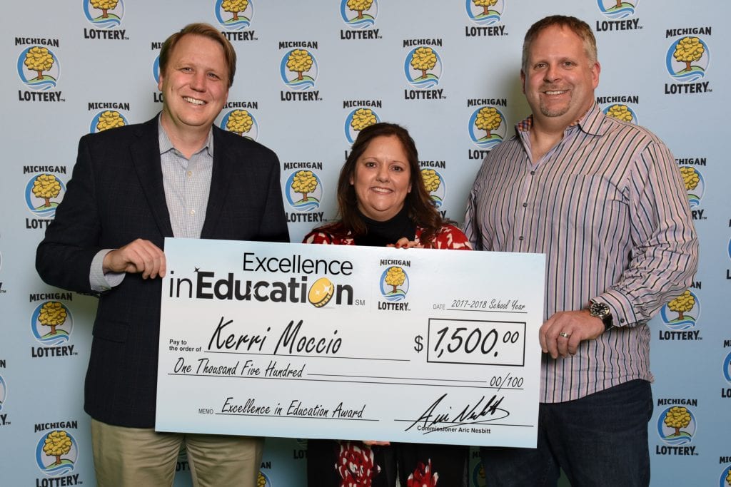 Photo courtesy of the Michigan Lottery Public Relations Division Kerri Moccio (center) and her husband, Craig (right) accepts her Excellence in Education Award from Michigan Lottery Commissioner Aric Nesbitt.